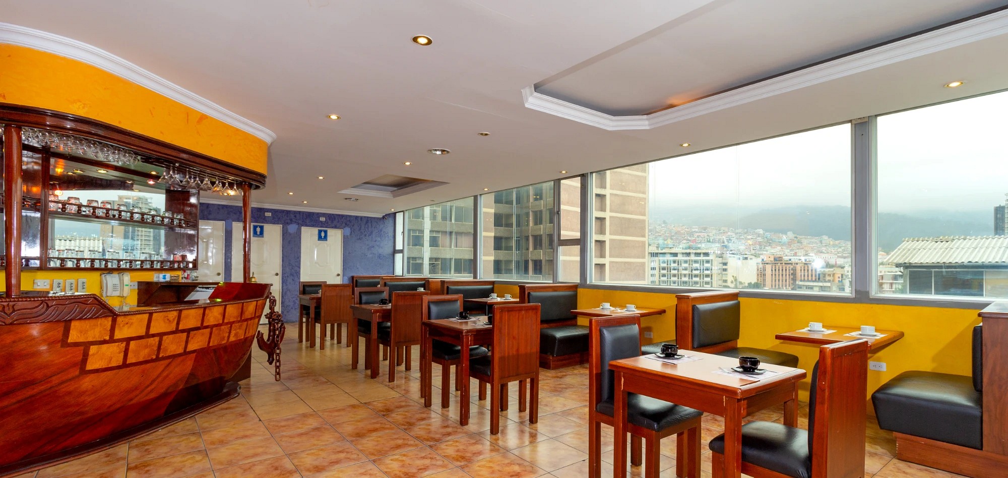 Comedor del hotel con ventanales y vista a la ciudad de Quito