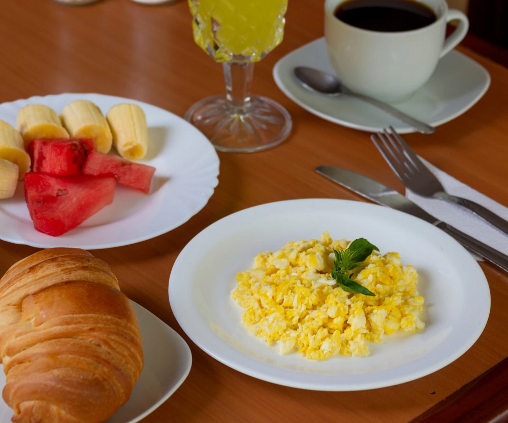 Desayuno continental: huevos revueltos, fruta, pan, jugo y café