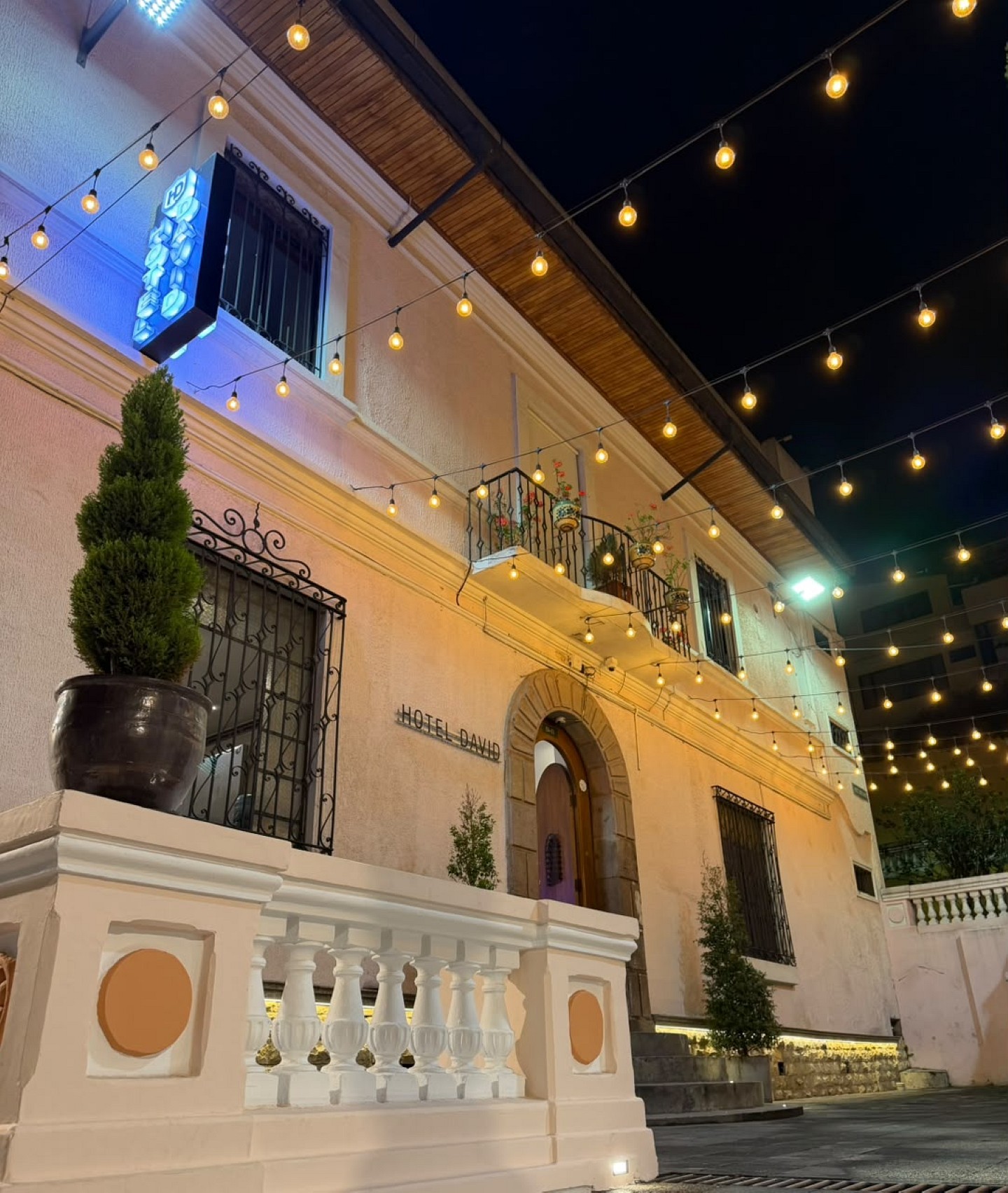 Fachada colonial del Hotel David iluminada de noche, con luces colgantes, balcón de hierro y la puerta en arco