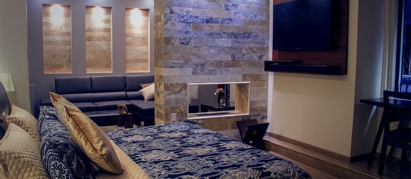 Cama de la suite con la sala y la columna de piedra al fondo