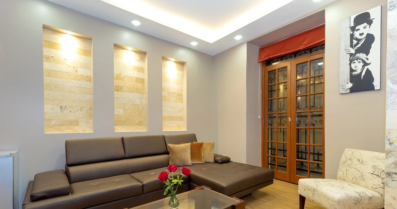 Sala de estar de la suite con sofá de cuero, mesa de vidrio y puerta al balcón