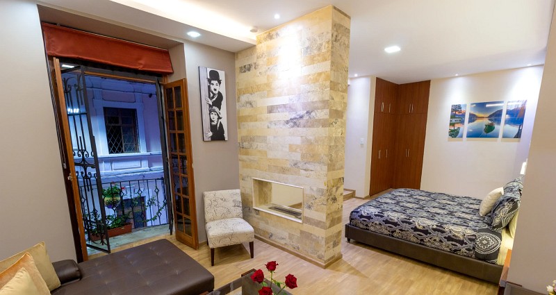 Suite Deluxe con sala de estar, balcón abierto y cama al fondo