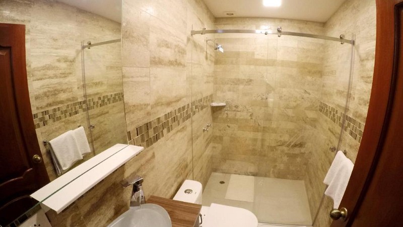 Baño de mármol con ducha de vidrio de la habitación de dos camas más amplia