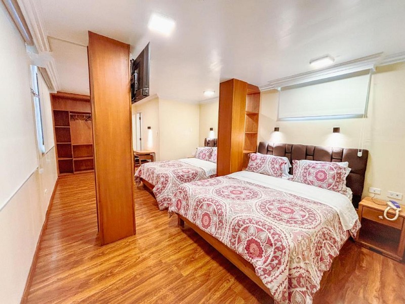 Habitación con dos camas, divisor de madera y piso de madera