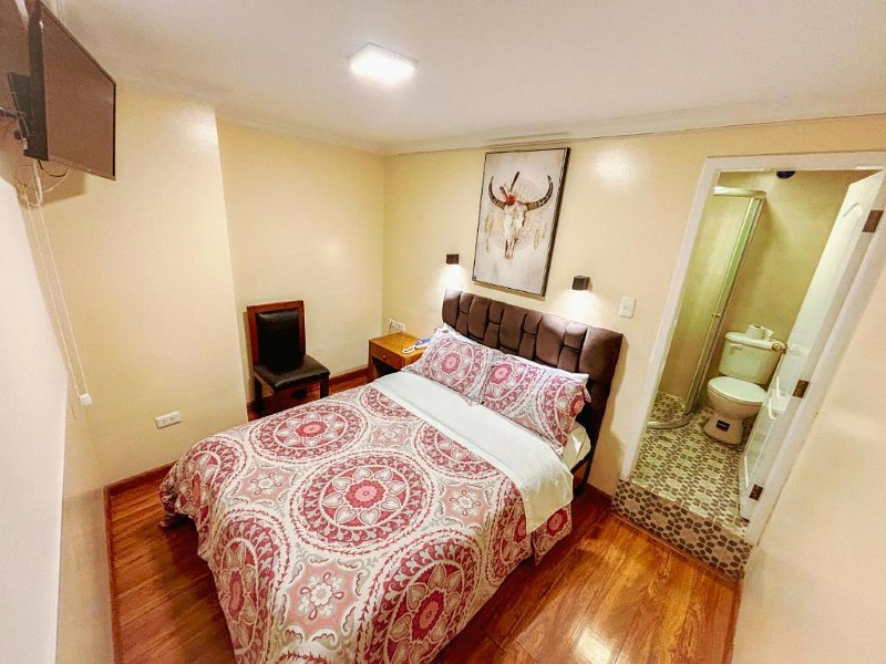 Habitación individual con cama, piso de madera y baño privado