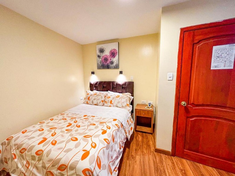 Habitación individual con mesita de noche y piso de madera