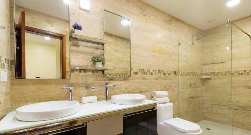 Baño de mármol con doble lavabo y ducha de vidrio