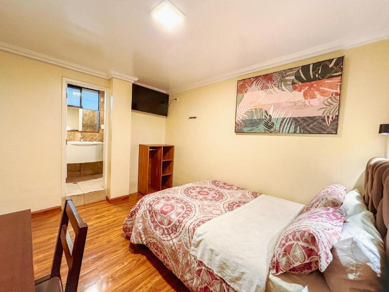 Habitación matrimonial con cuadro grande y baño privado a la vista