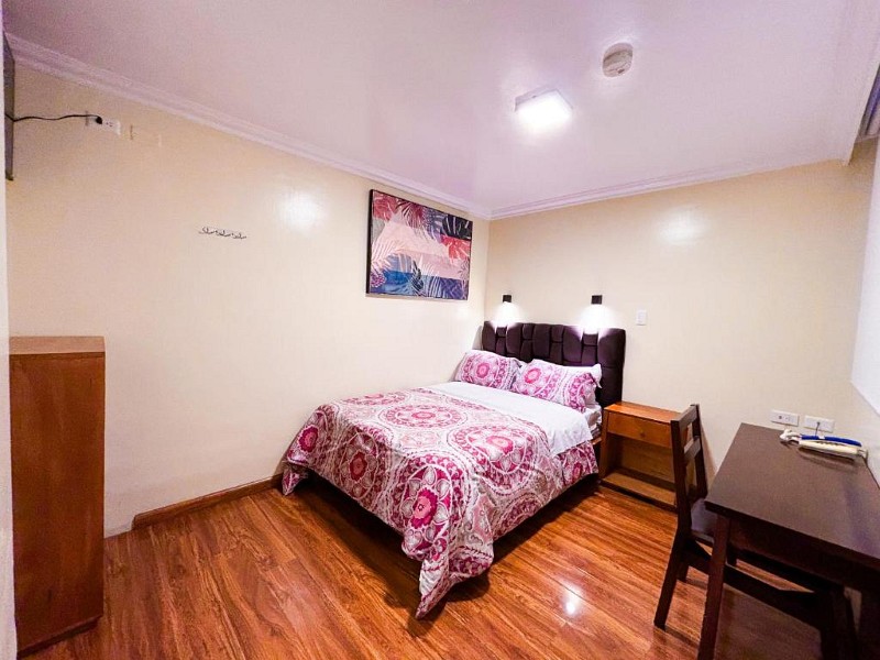 Habitación matrimonial con cuadro tropical y escritorio