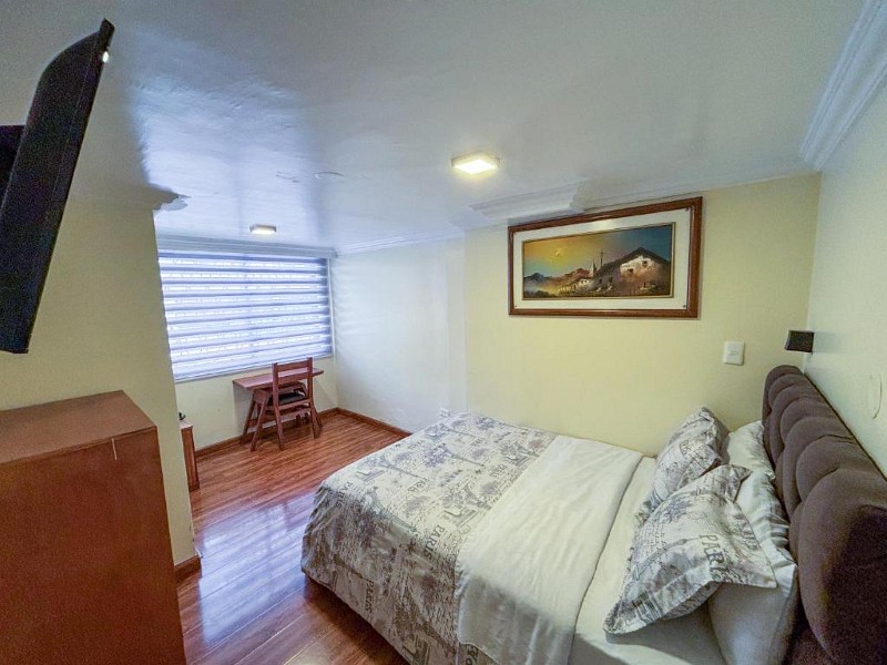 Habitación matrimonial con escritorio junto a la ventana y cuadro