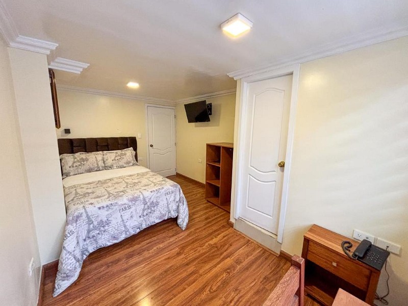 Habitación matrimonial con piso de madera y televisión
