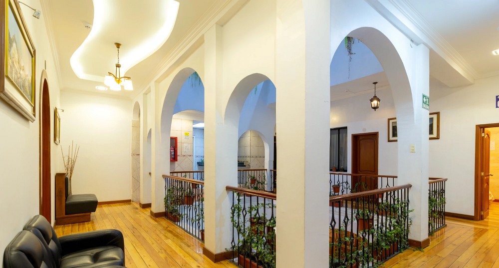 Pasillo con arcos blancos y piso de madera junto al patio