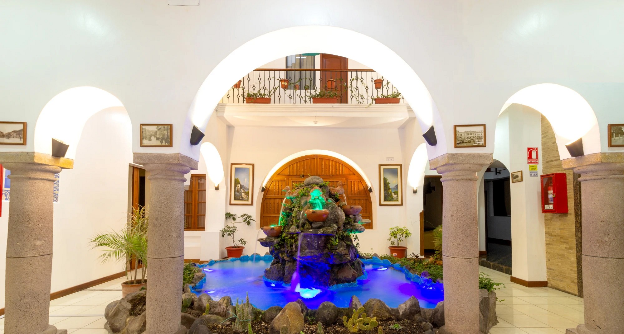 Patio central del Hotel David con la fuente iluminada y arcos de piedra
